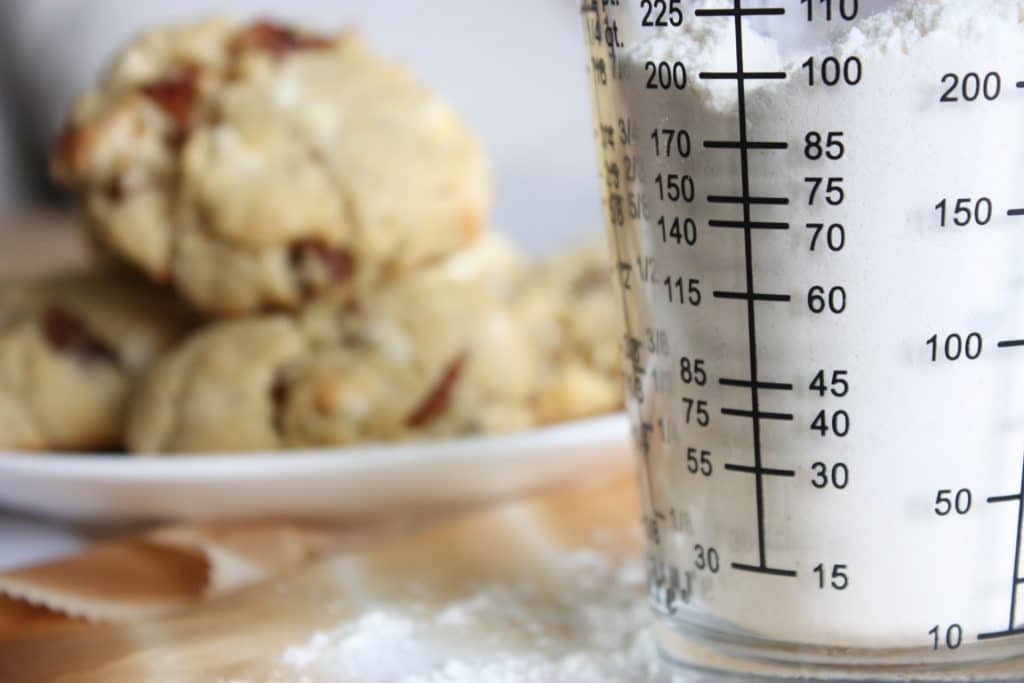 A measuring cup with ounces to quarts conversion and cookies